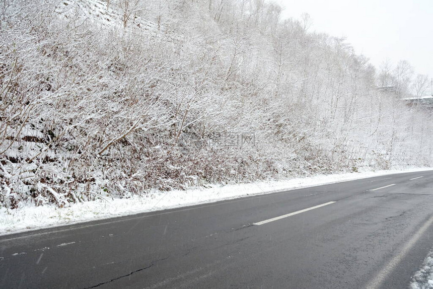 在雪背景的冬天山的柏油路图片