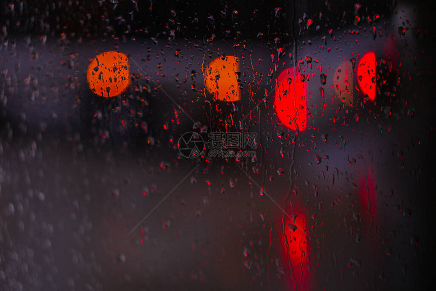 望向雨下街道的窗口路面明亮的夜晚天气汽车玻璃上的滴水和汽车上的bokeh图片