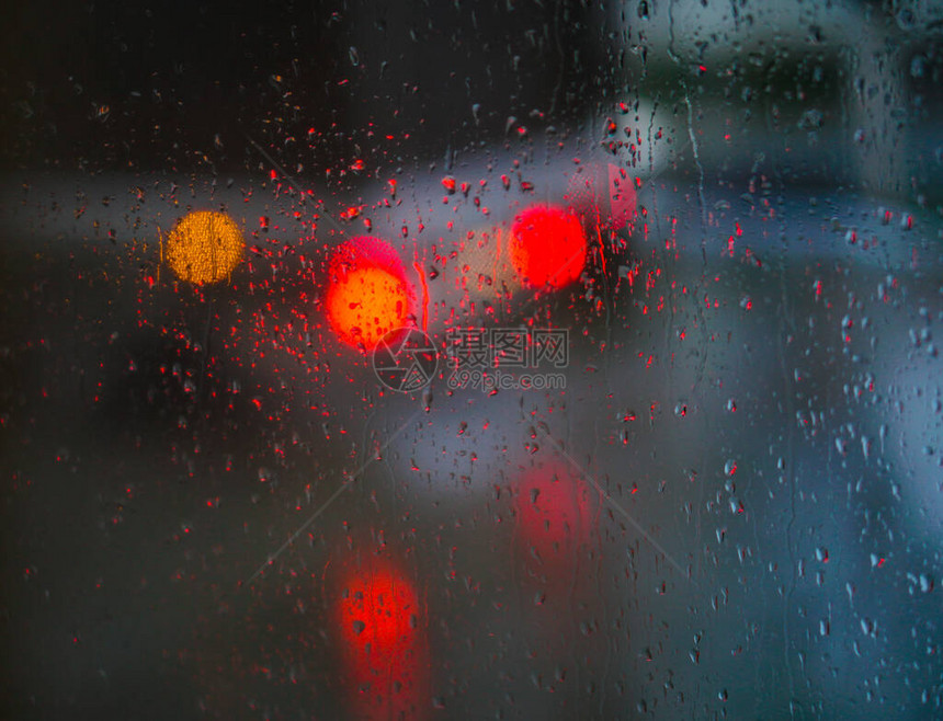 望向雨下街道的窗口路面明亮的夜晚天气汽车玻璃上的滴水和汽车上的bokeh图片