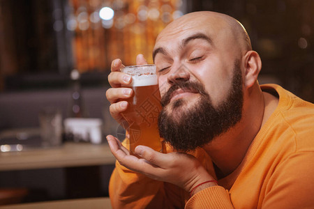 一个快乐的大胡子男人抱着一杯啤酒的特写爱他的啤图片