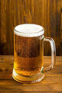 一杯带有泡沫的啤酒放在木桌上图片