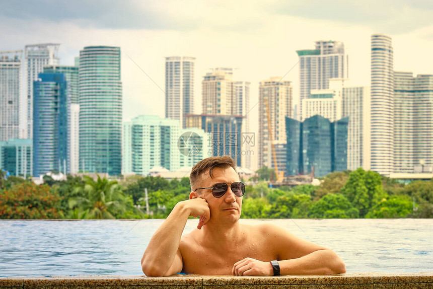 一个人在酒店屋顶的游泳池里从豪华的五星级DiscoveryPrimea酒店的游泳池欣赏马尼拉市的景色天气晴朗背景图片