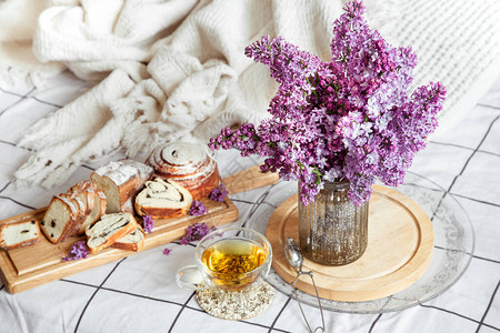 早餐或早午餐在床上享用糕点和茶花瓶里的丁香花浪漫和假期母图片