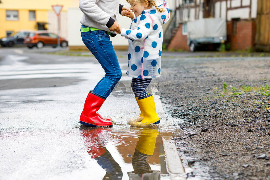 在雨夹雪中行走快乐的兄弟姐妹兄弟姐妹跳进水坑在户外玩得开心图片