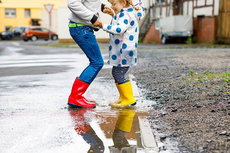 在雨夹雪中行走快乐的兄弟姐妹兄弟姐妹跳进水坑在户外玩得开心背景图片