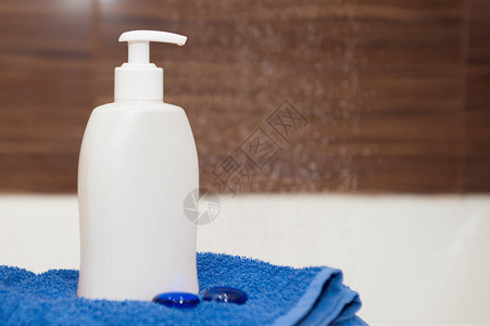 浴室里有一瓶白肥皂洗发水和蓝色毛巾复制空间图片