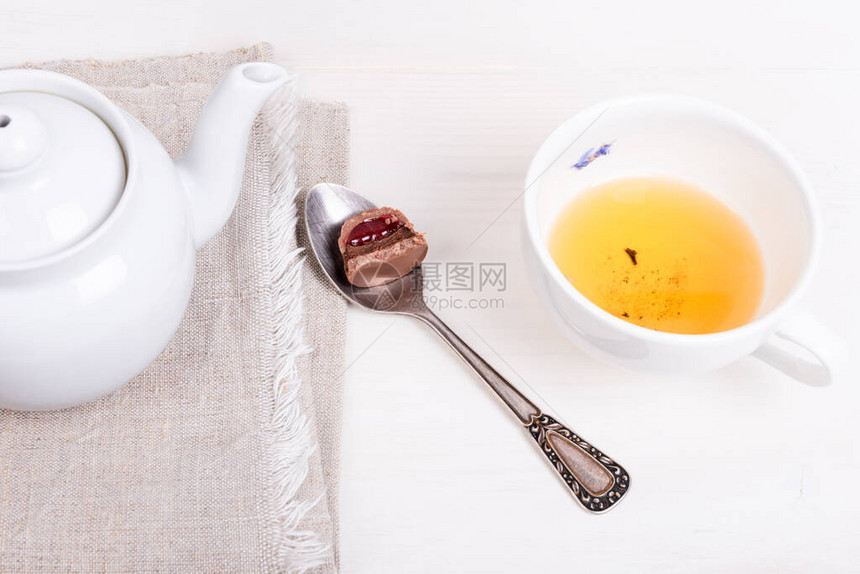 餐巾纸上的茶壶喝醉的日本绿花茶的杯子和带糖果的勺子图片
