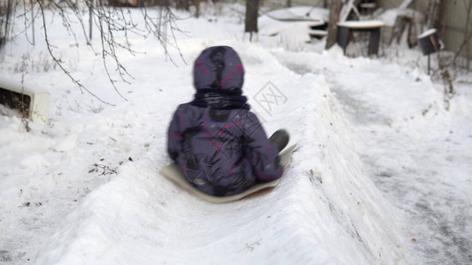 一个孩子在雪滑梯上打滚街上的冬季乐趣在寒冷的冬天图片