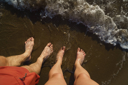 在泡沫海浪中的沙子上裸脚的顶端景色图片