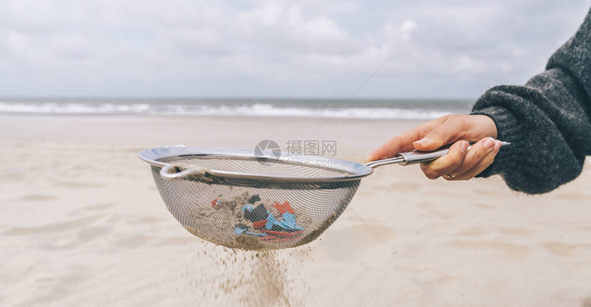 年轻女从沙滩上的沙子中清洁微塑料环境问题污染生态系统和气候图片