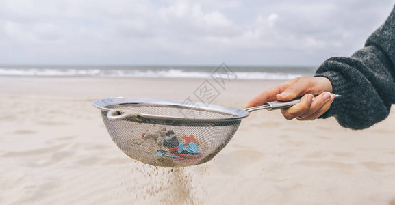 年轻女从沙滩上的沙子中清洁微塑料环境问题污染生态系统和气候图片