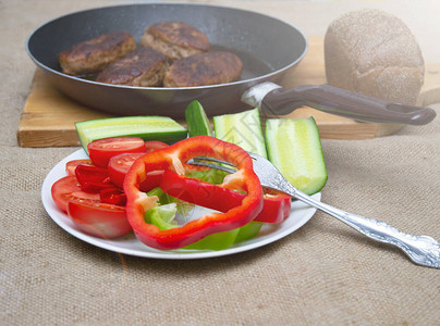 蔬菜胡椒和黄瓜放在牛肉饼旁边的盘子上图片