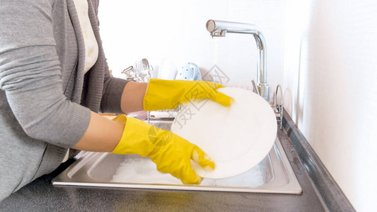 年轻家庭主妇穿着橡胶手套洗碗在厨房图片