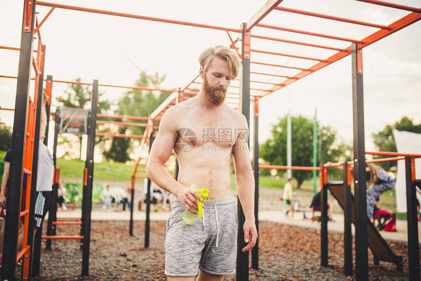 运动型肌肉男在街头健身房锻炼后从运动瓶中喝水口渴的人在户外训练后喝水健身运动生活方式的概念保图片