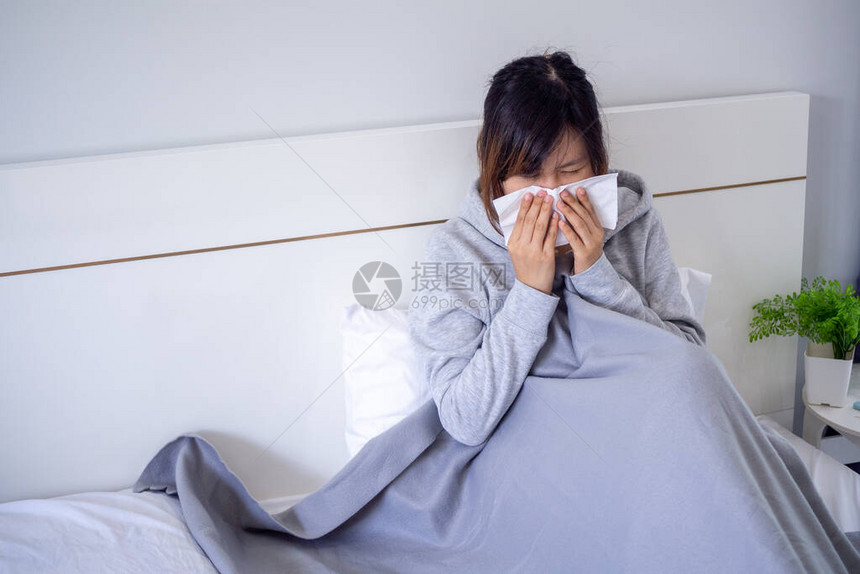 生病的女人坐在毯子下面打鼻涕图片