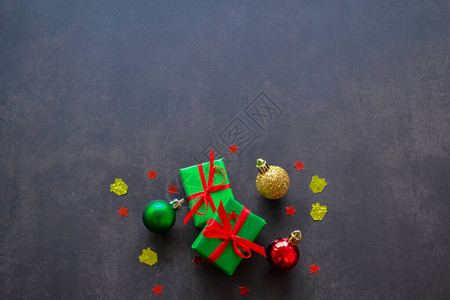 用红色和黄色丝带红色和绿色圣诞球和红星形式的五彩纸屑制成的绿色纸礼物图片