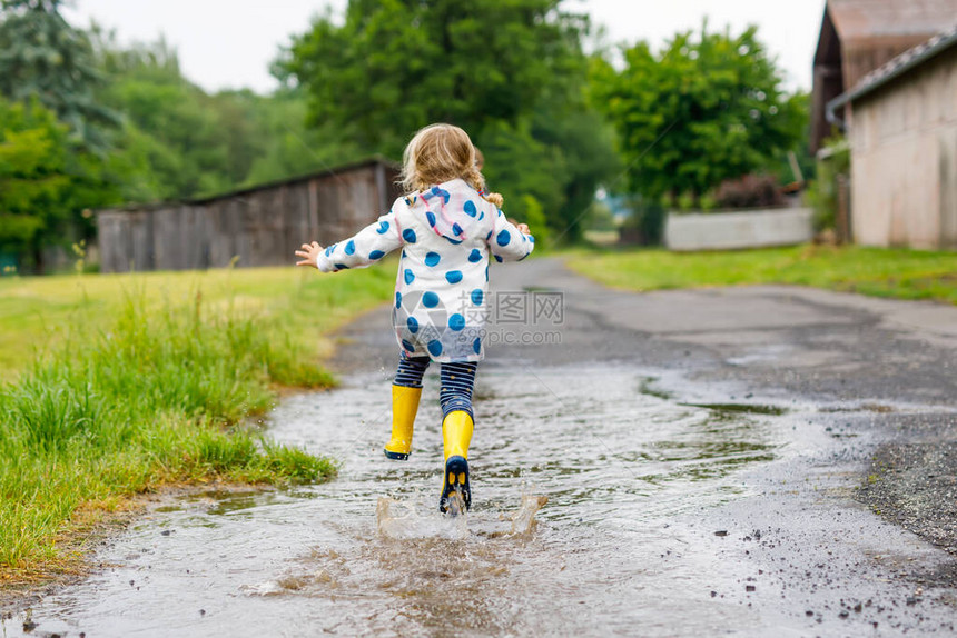 蹒跚学步的小女孩穿着黄色雨靴图片