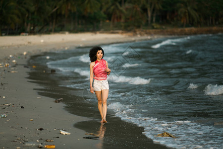 亚洲妇女沿着被污染的热带海滩行走环境问图片