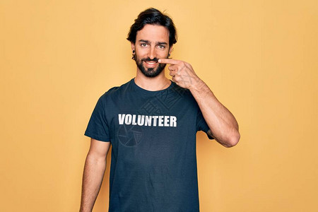年轻英俊的西班牙裔志愿者男子穿着志愿T恤作为社会关怀图片