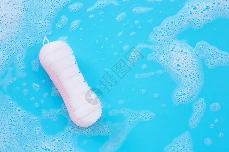 在蓝色背景下用粉末洗涤水溶解泡沫清洗衣服的刷子图片