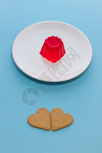 白色盘子上的草莓果冻甜点两块心形饼干图片