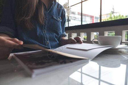 一位女在现代咖啡馆开书时用咖啡杯放在桌背景图片