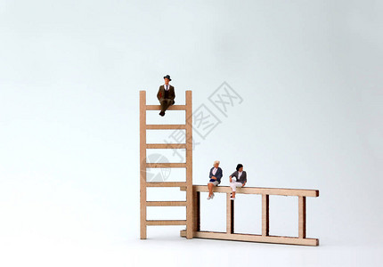 一个小男人和女人坐在木制梯子上以男为导向的权图片
