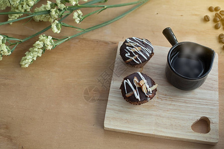 木制背景上的美味蛋糕木托盘上的杯子里的热咖啡桌上的咖啡豆图片