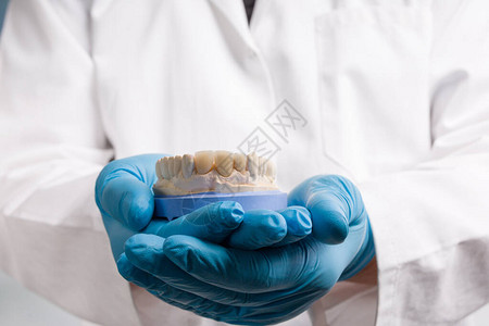 口腔技术员手握的手套上贴有牙印和人造凹痕的手套图片
