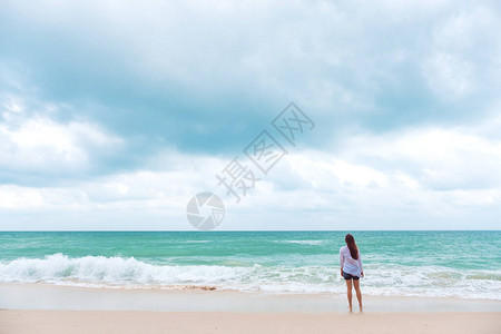 一位站在海滩上看风景的女士带着海和蓝天图片