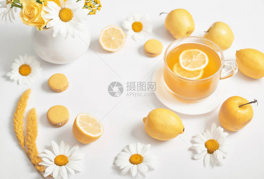 春夏卡带柠檬片的雏菊茶杯与鲜花洋甘菊在杯子里的凉茶维生素图片