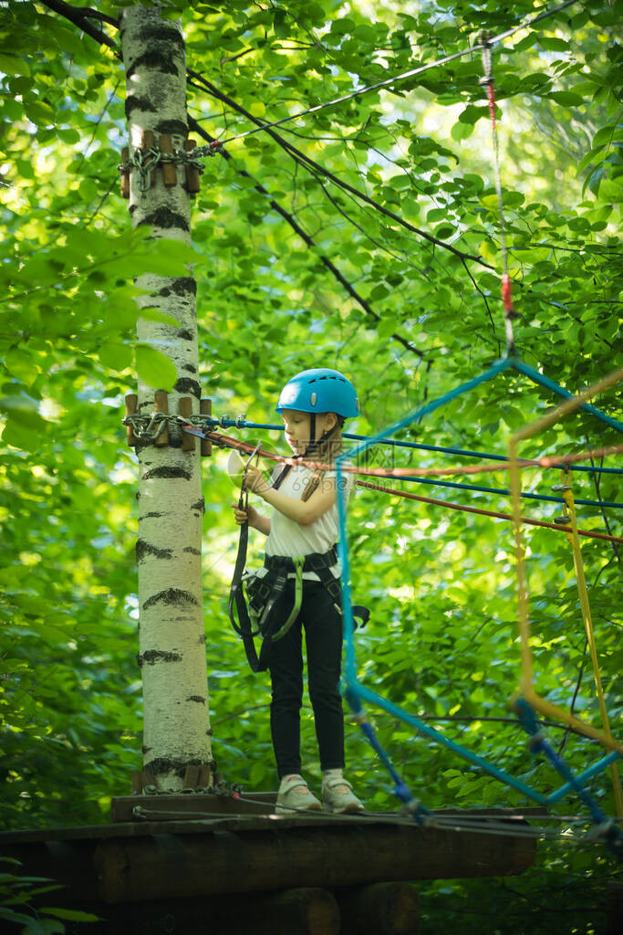 森林里的极限绳索冒险一个小女孩站在树上的架子上等待她图片
