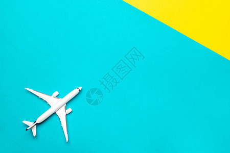 平面横幅明亮的蓝色和黄色背景上的白色玩具飞机在天空中飞行图片