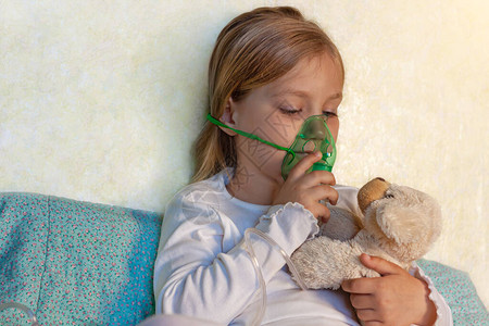 小女孩在家里的床上用雾化器吸入生病的过敏儿童哮喘吸入器蒸汽咳嗽儿童过敏概念呼吸系统疾病肺部药物治疗季背景图片