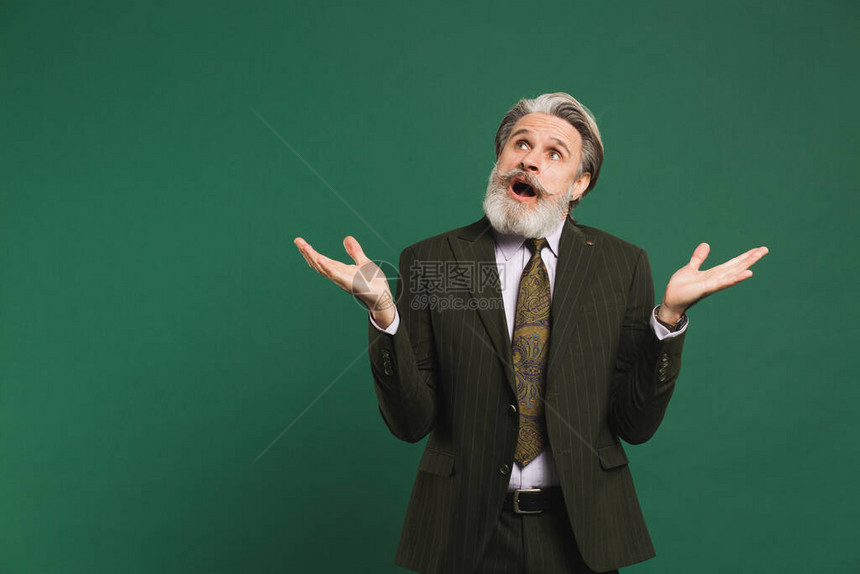 身穿卡其西服的中年大胡子男在绿色背景和复制图片