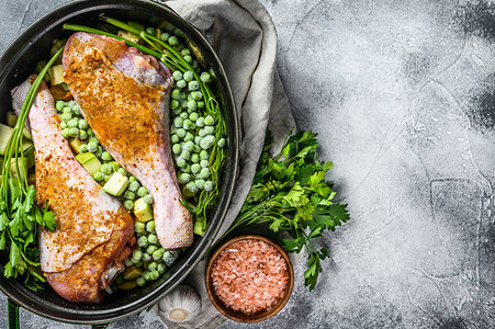 火鸡炖肉用欧芹豌豆芹菜和土豆制作鸡腿的食谱灰色背景顶视图图片