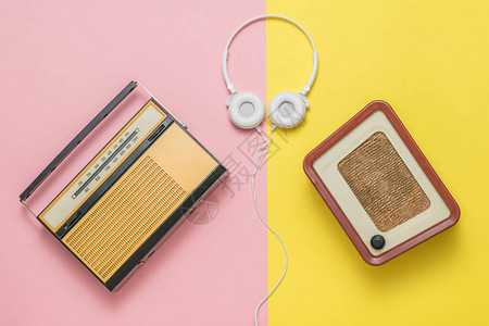 两台黄色和粉红色背景的复古收音机和耳机图片