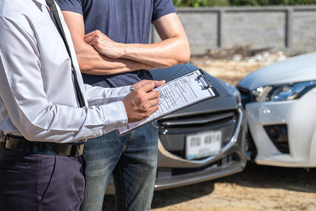 保险代理商在报告索赔表程序上检查事故后汽车的损坏情况图片