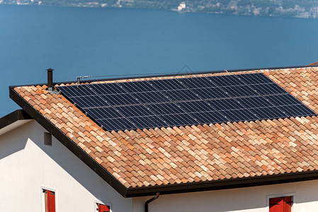 以蓝湖为背景的房屋顶上的太阳能电池板图片