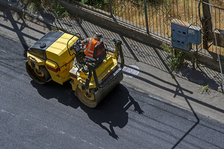 沥青施工程的鸟瞰图与商业维修设备道路停车与黄色压路机的汽车图片