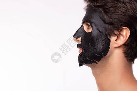 美肤焕颜英俊的年轻人在面部皮肤上涂保湿剂使黑色面膜恢复活力背景