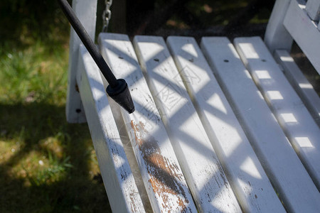 高压清洗机在乡间别墅花园的白色木凳上留下油漆图片