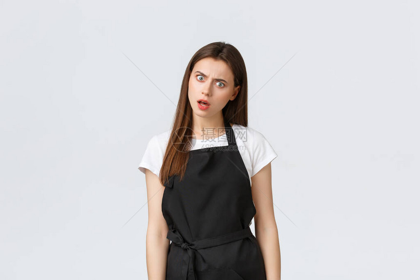 小型企业员工和咖啡店概念黑色围裙的困惑和困扰的可爱咖啡师难以置信地凝视着心烦意乱的女咖啡馆工作人员凝视图片