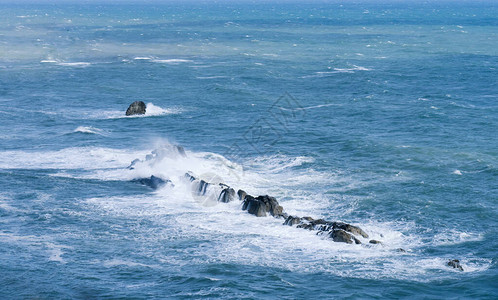 夏天海浪拍打岩石的海景海浪溅起图片