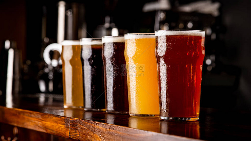 许多品种的精酿啤酒木条上带有麦酒啤酒深色浅色和未经过滤的饮料的雾状玻璃酒杯图片