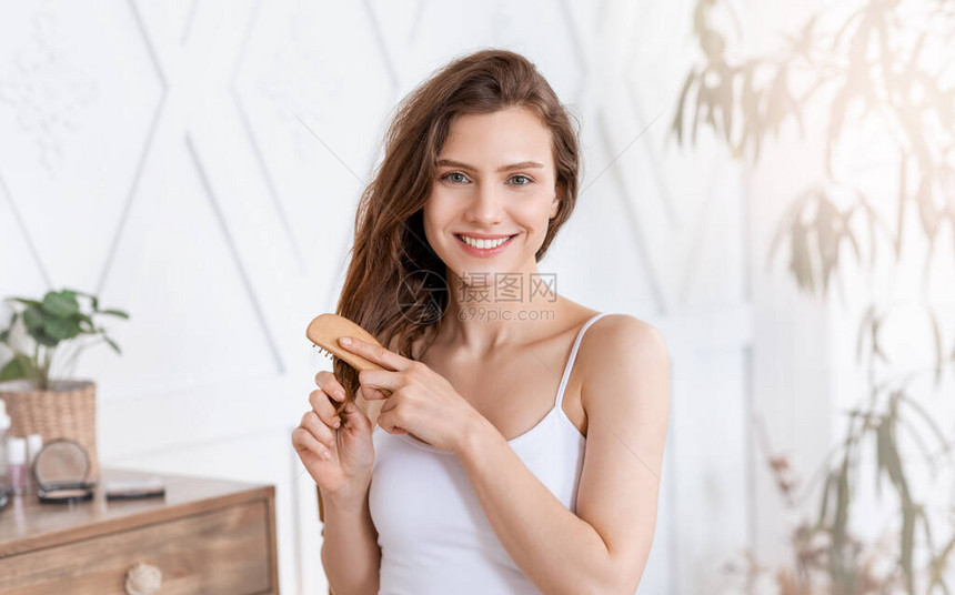 微笑着有魅力的年轻女子在家梳理头发晨美常图片