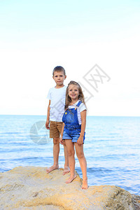 两个孩子在海边的岩石上夏天兄弟姊妹们在图片