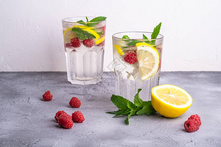 石混凝土背景的两面玻璃杯中加入柠檬覆盆子水果和薄荷叶的新鲜冷冰水饮料图片