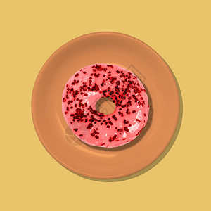 红色甜圈在黄色背景的橙色盘子上图片