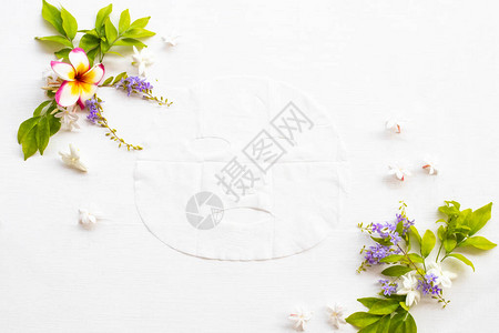 天然香气片状面膜提取物草本精华面膜保健皮肤面部与花卉排列平躺风背景图片